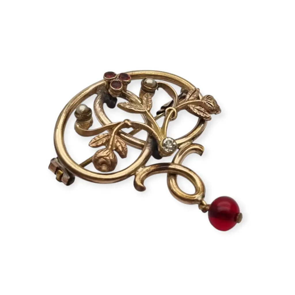 Broche Art Nouveau dorado con flor calada perlas y granates Circa 1900.