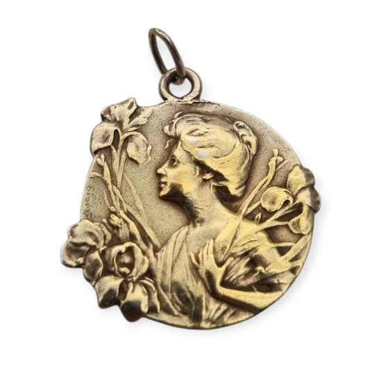 Medalla colgante Art Nouveau en plata dorada con mujer entre lirios firmada E.
