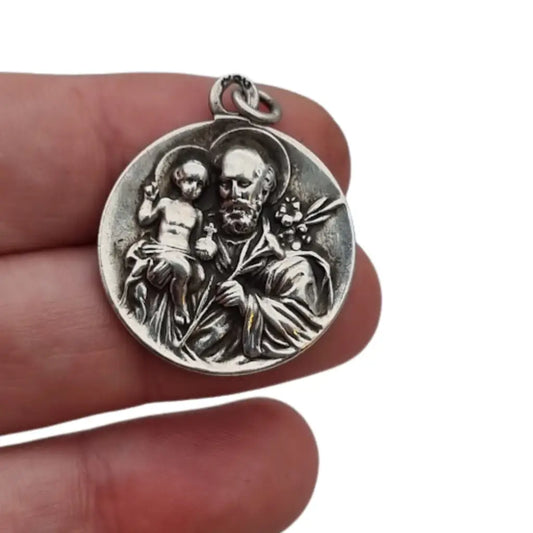 Medalla religiosa antigua en plata maciza de San José y el Niño fechada 1920.