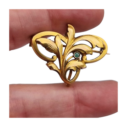 Broche FIX Art Nouveau laminado en oro con piedra verde y diseño floral, circa 1920