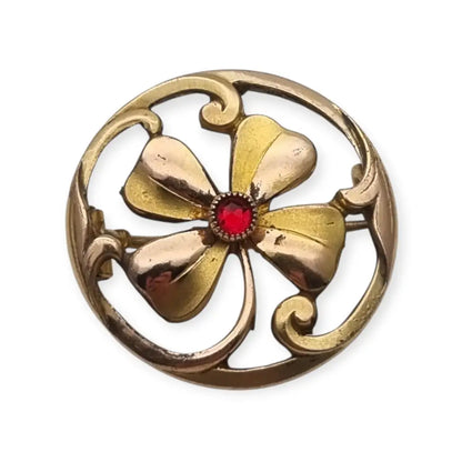 Broche antiguo Art Nouveau en metal dorado flor calada con cristal rojo central