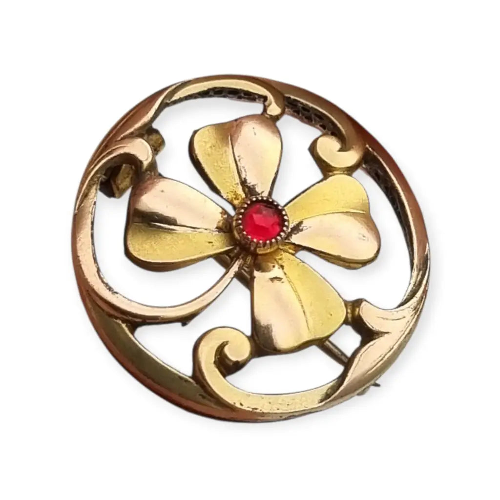 Broche antiguo Art Nouveau en metal dorado flor calada con cristal rojo central