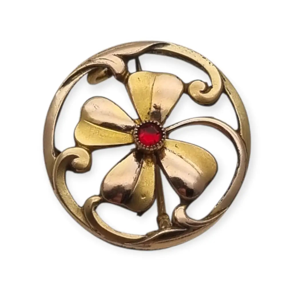 Broche antiguo Art Nouveau en metal dorado flor calada con cristal rojo central