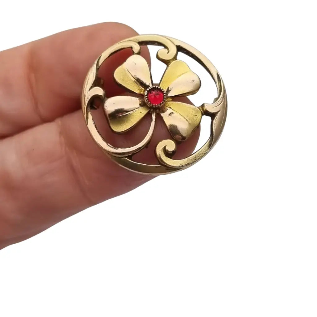 Broche antiguo Art Nouveau en metal dorado flor calada con cristal rojo central