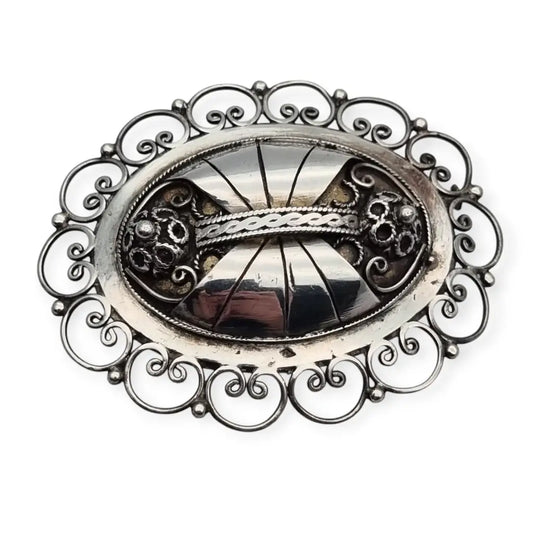 Broche ovalado de plata con filigrana popular detallada y diseño Art Nouveau.