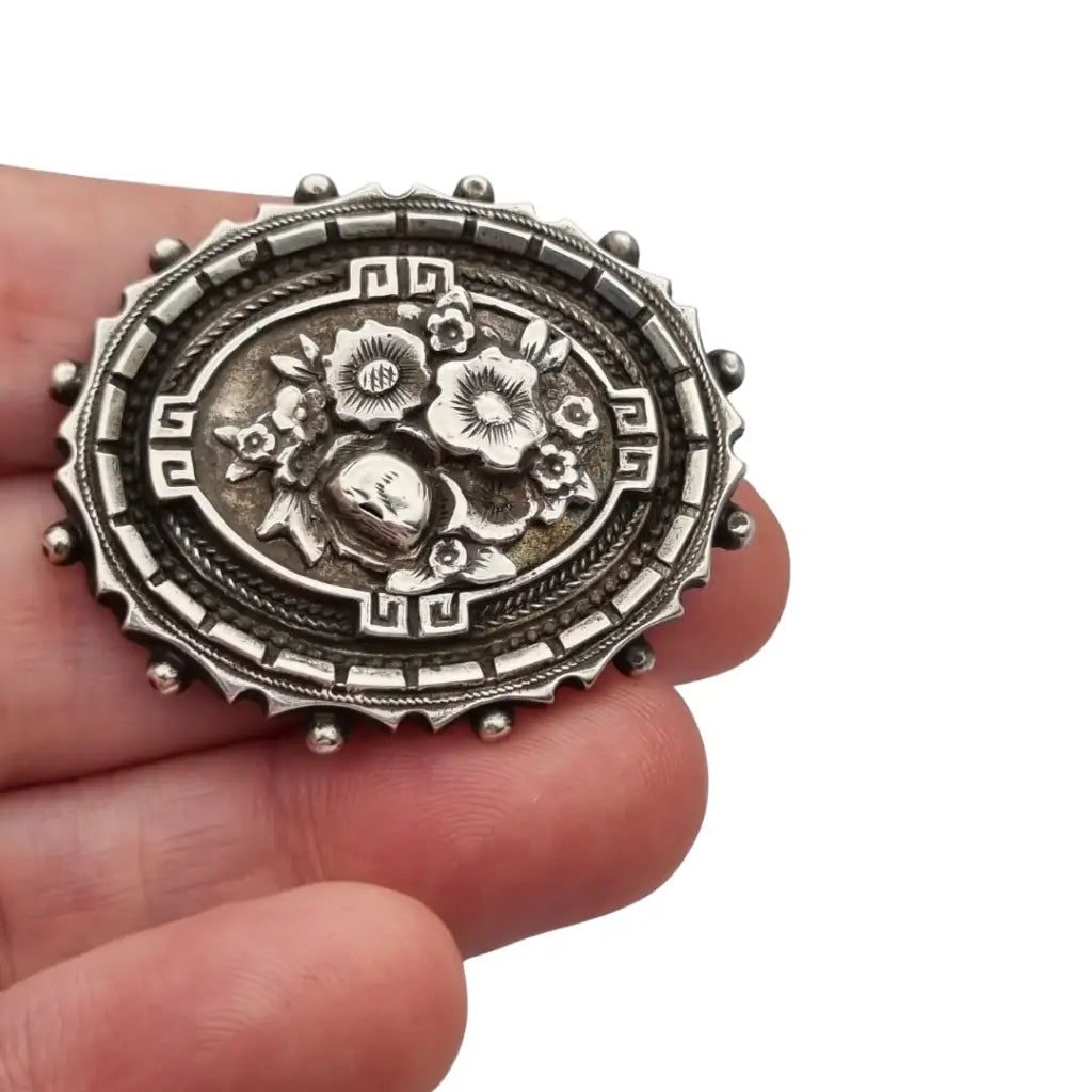 Broche relicario victoriano en plata de ley con flores relieve. Circa 1910.