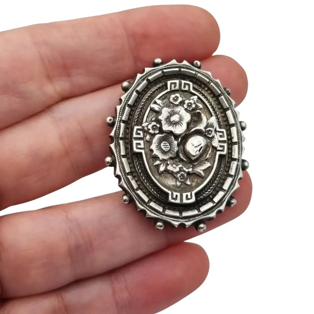 Broche relicario victoriano en plata de ley con flores relieve. Circa 1910.