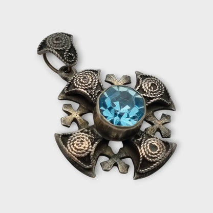 Colgante cruz maltesa de metal plateado con piedra azul decoración
