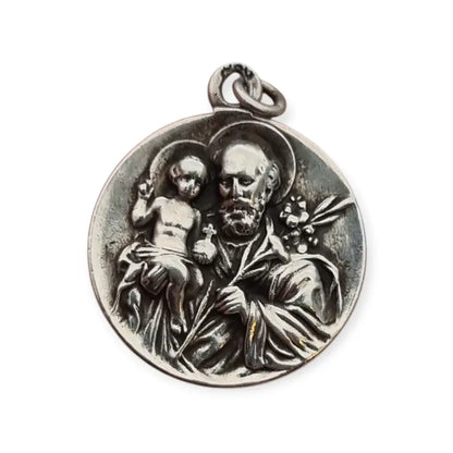 Medalla religiosa antigua en plata maciza de San José y el Niño fechada 1920.